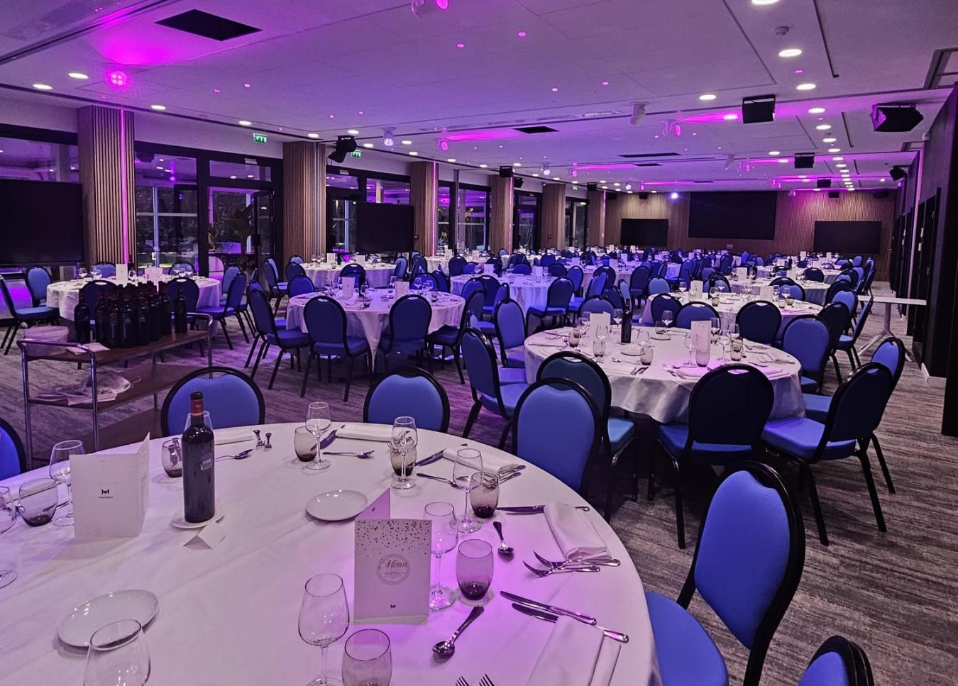Banquet room set with round tables under ambient lighting