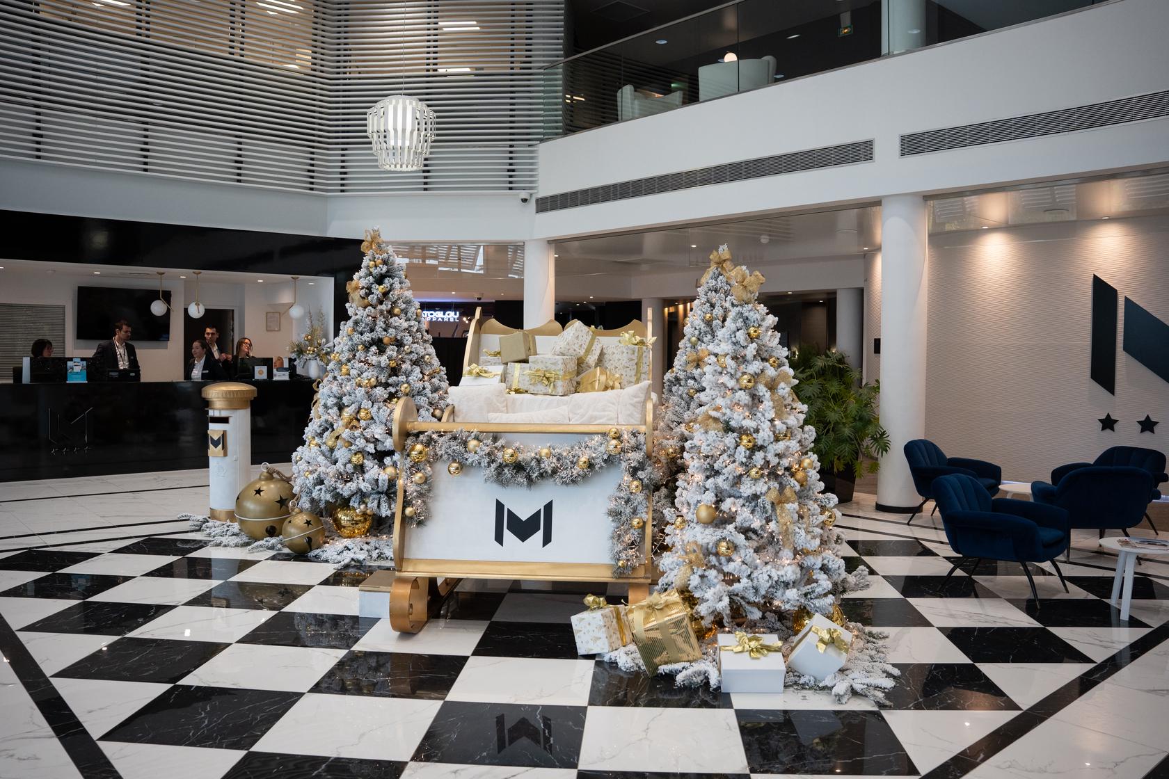 The resort lobby decorated for Christmas: golden sleigh, snow-dusted trees and gifts