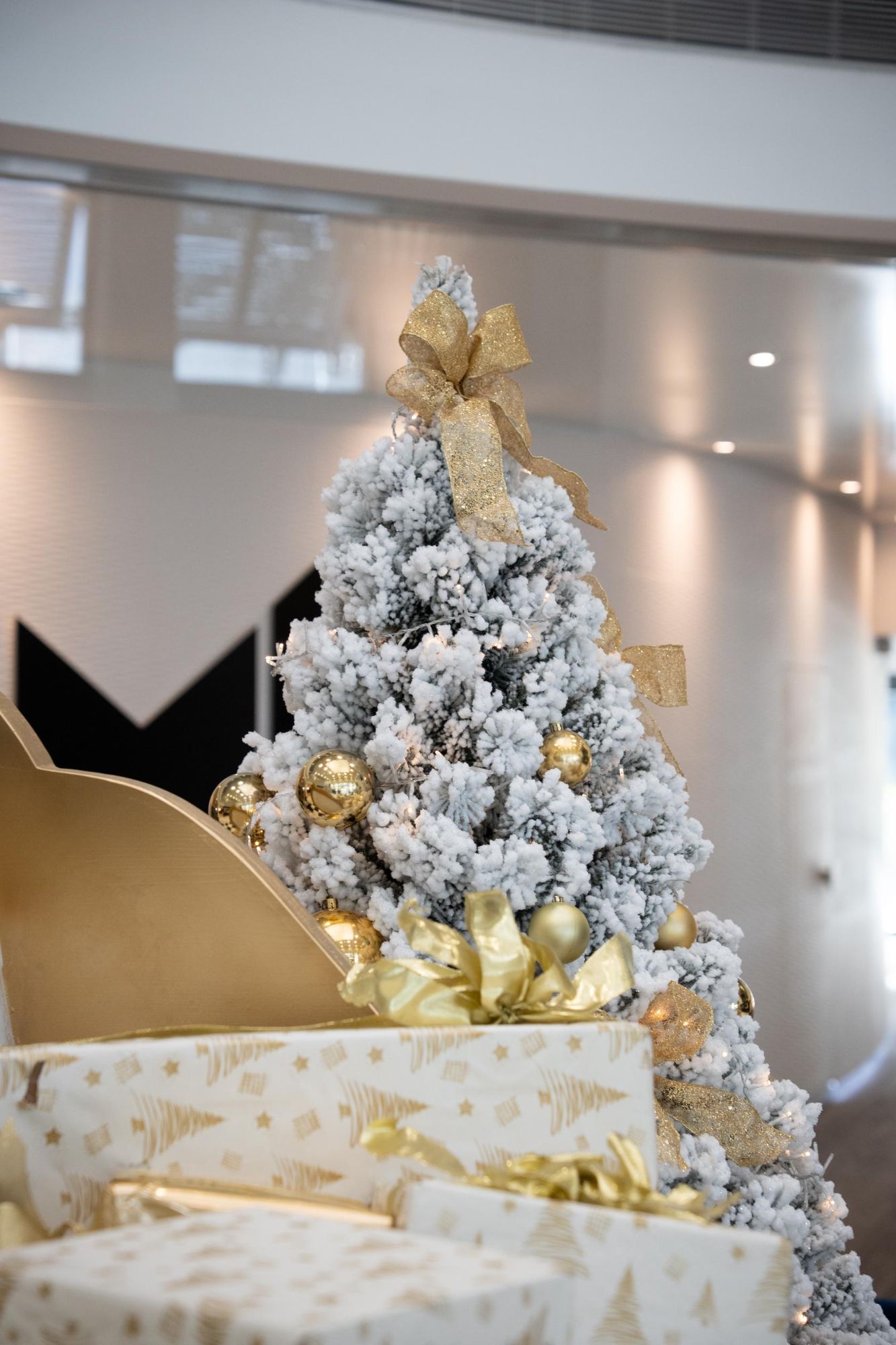 Snow-dusted Christmas tree with gold baubles and ribbons in the resort lobby